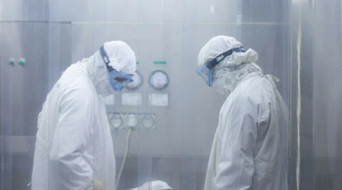 Two scientists in protective suits working in a cleanroom.